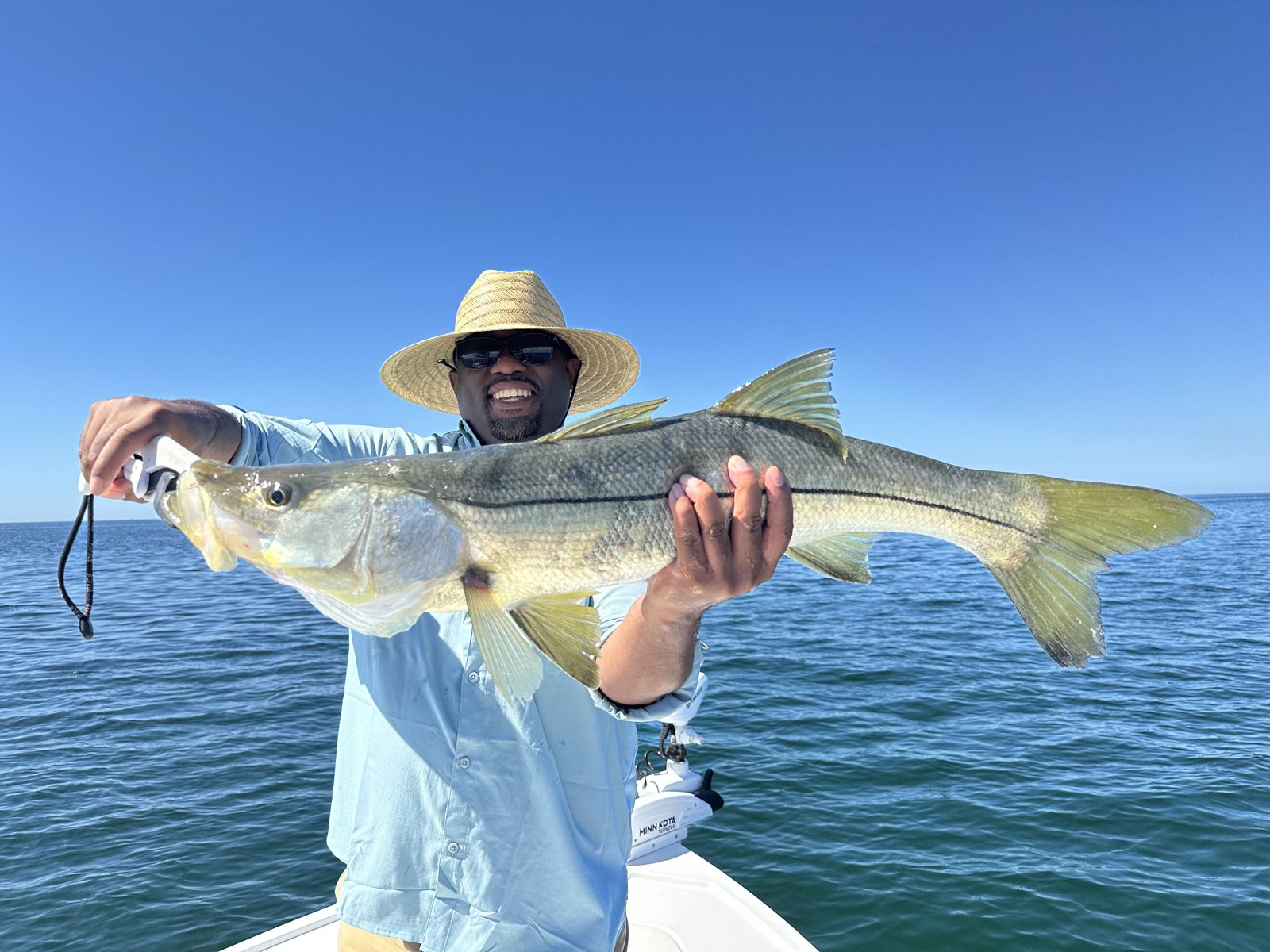 Angler in a straw hat with a long snook