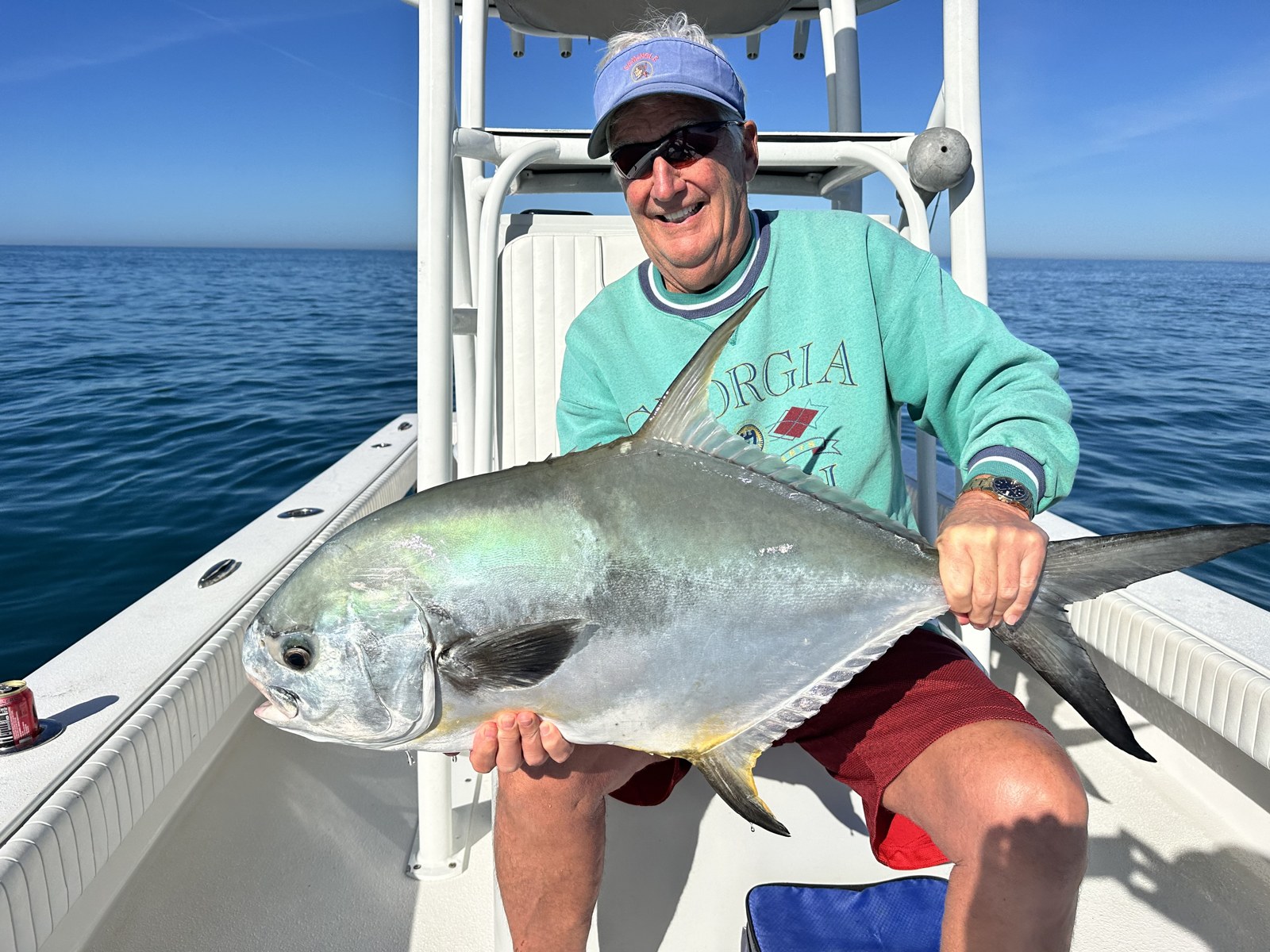 Smiling angler with a big permit on flat blue water