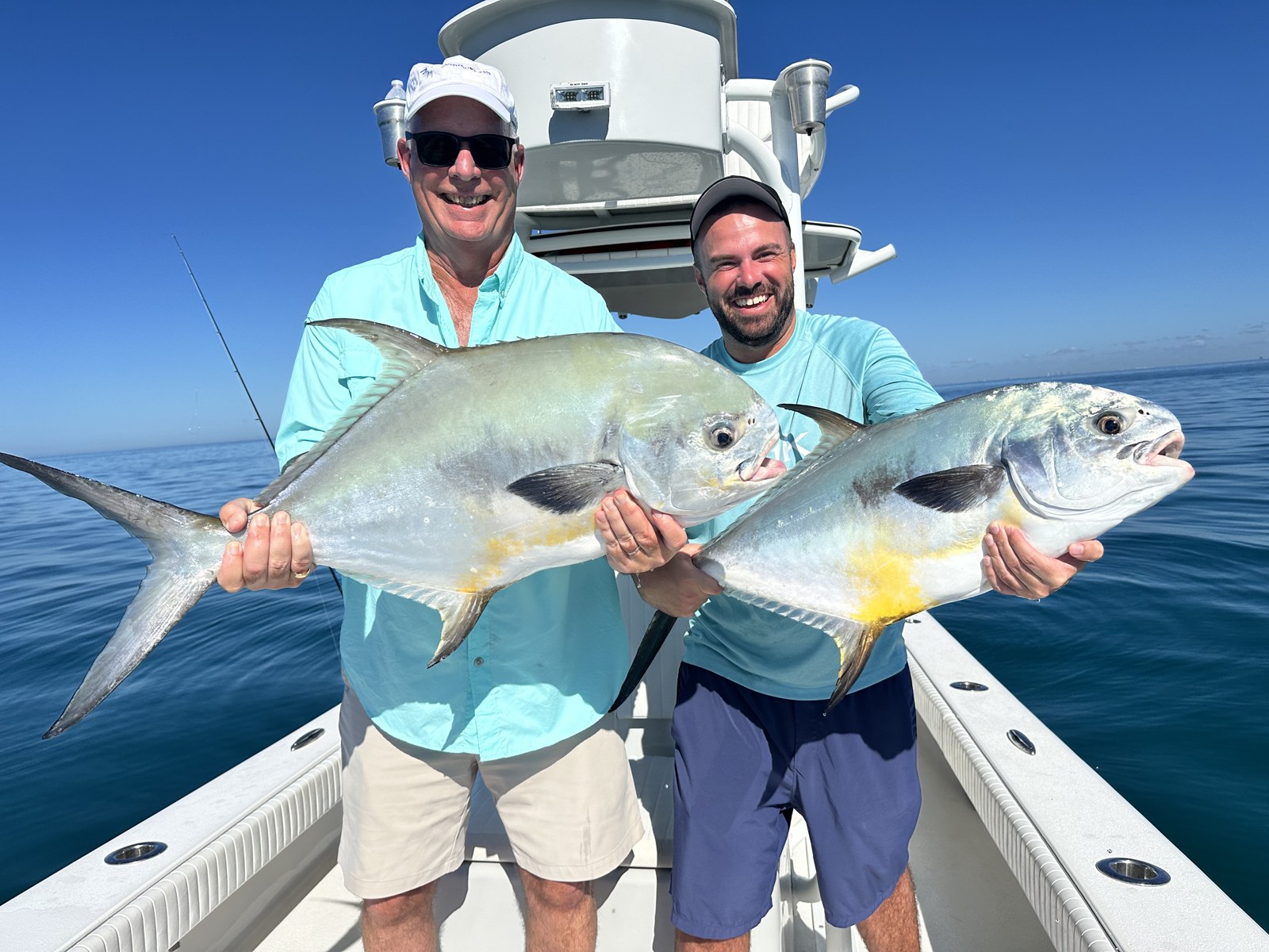 Two anglers holding a double-header of permit