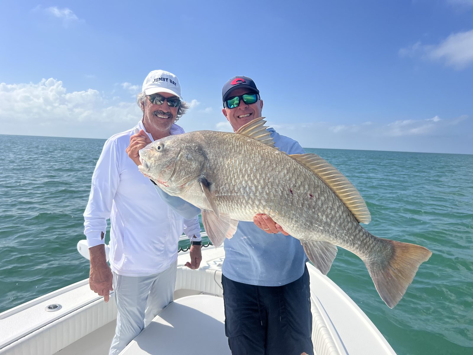 Two anglers holding a heavy black drum