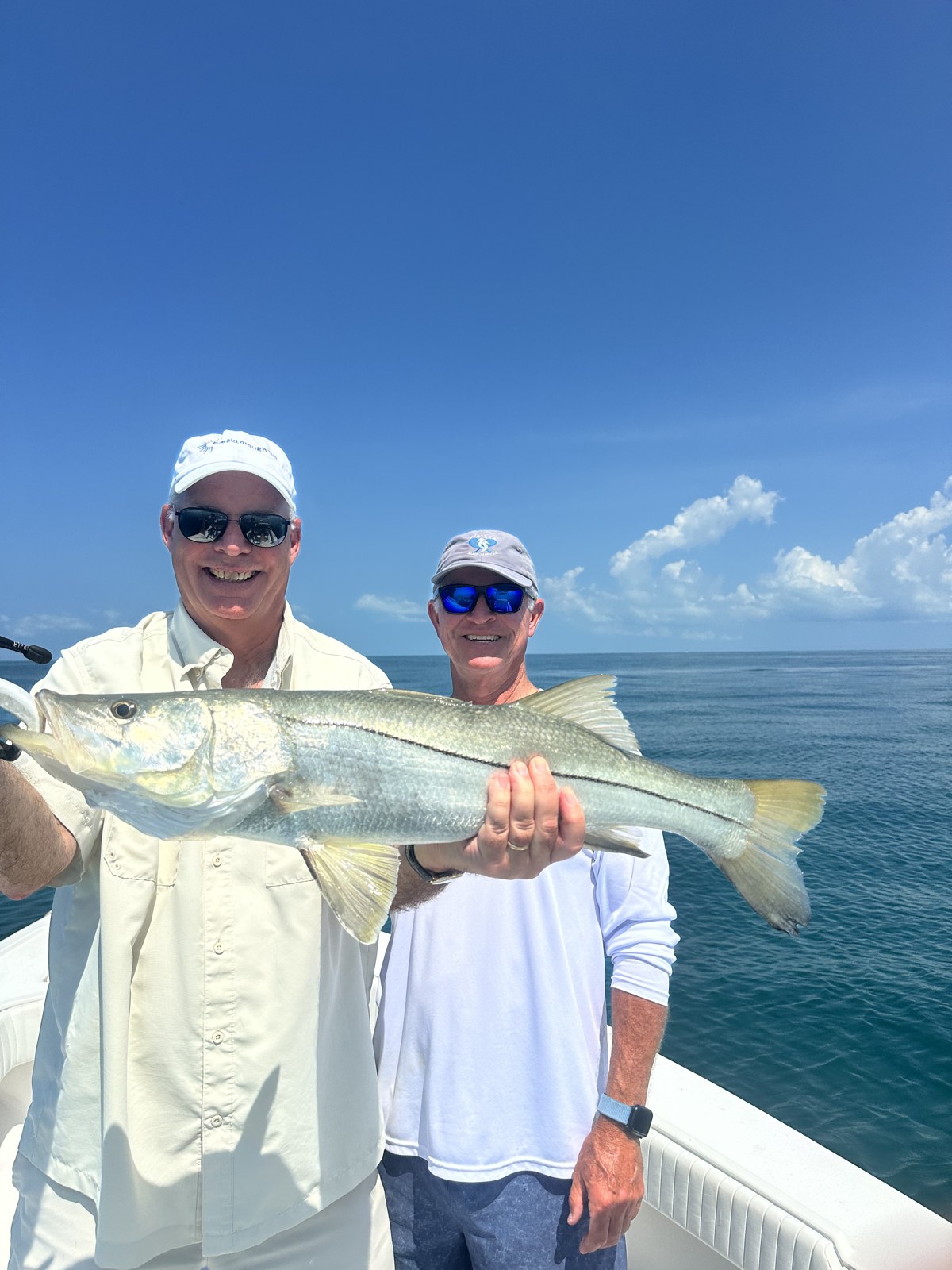 Pair of anglers with a bright snook on the blue Gulf
