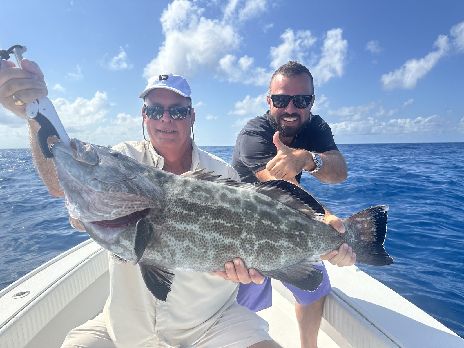 Two anglers with a big grouper in blue Gulf water