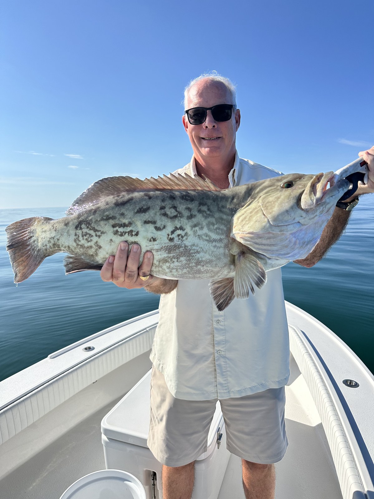 Angler holding a heavy gag grouper on calm water