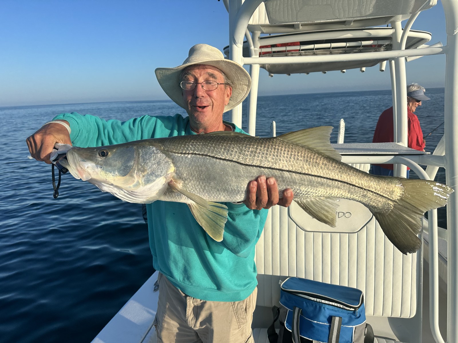 Angler in a straw hat with a thick snook on the Dorado