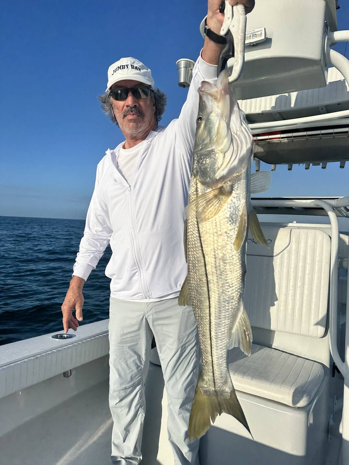 Angler holding up a tall snook alongside the console