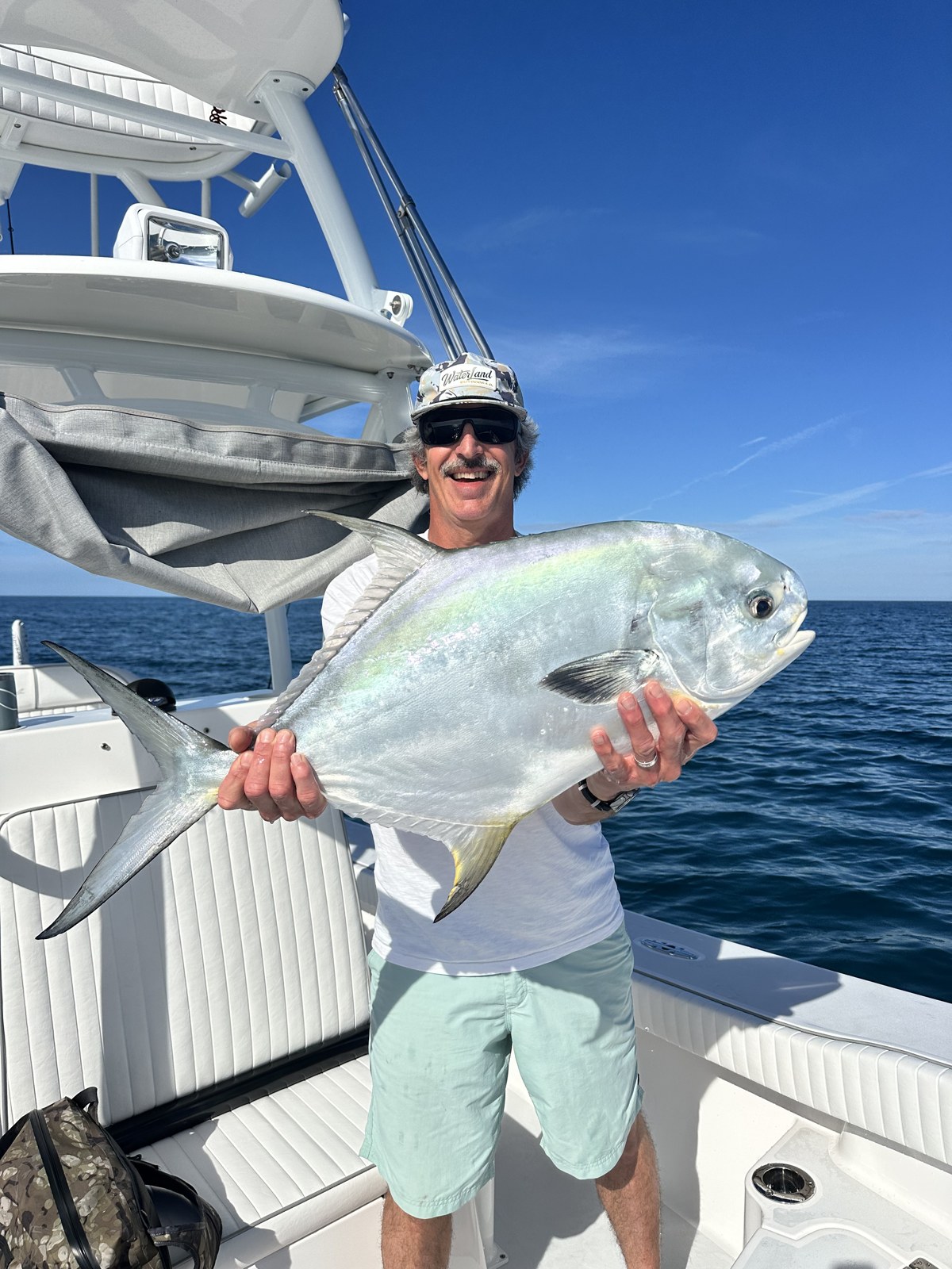 Angler holding a chrome permit alongside the tower boat