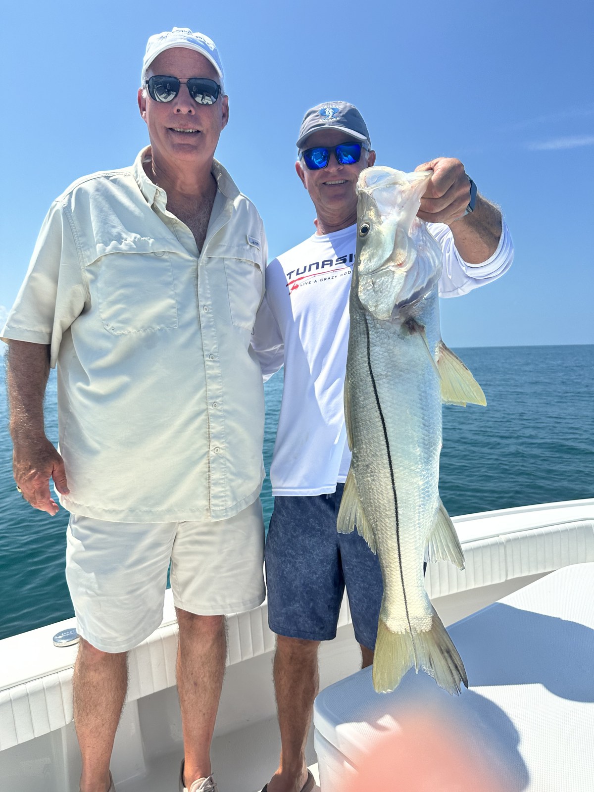 Angler holding up a tall snook offshore of Naples