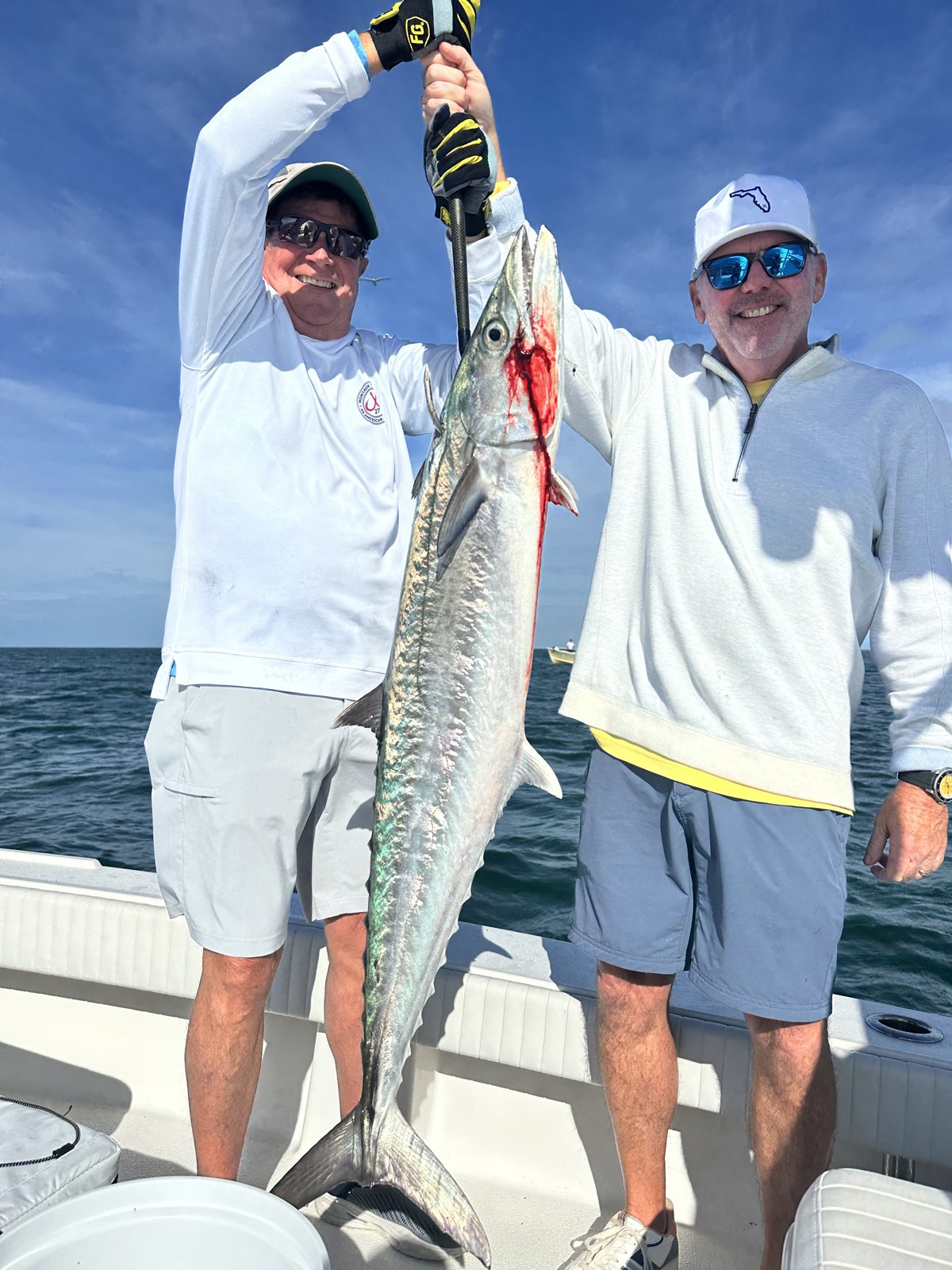 Two anglers hoisting a big kingfish on the Dorado