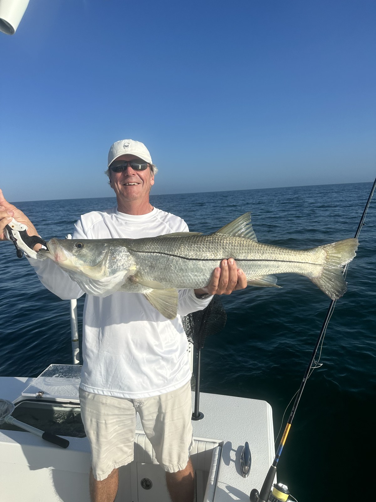 Smiling angler with a long snook on a calm Gulf morning